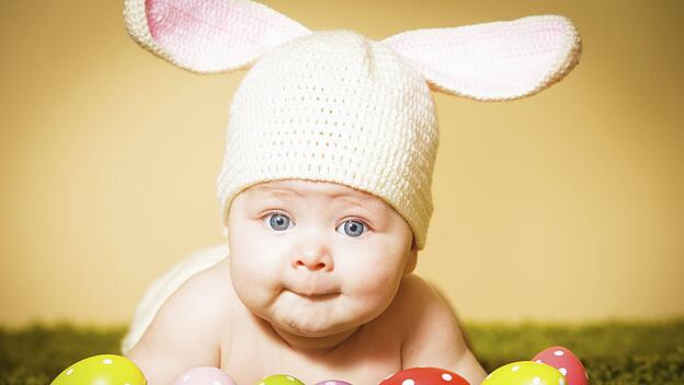 Baby mit Hasenmütze und Ostereiern