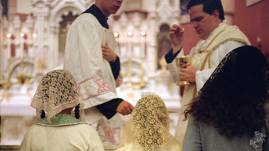 Katholiken knien im Rahmen einer Alten Messe, um die Kommunion zu erhalten