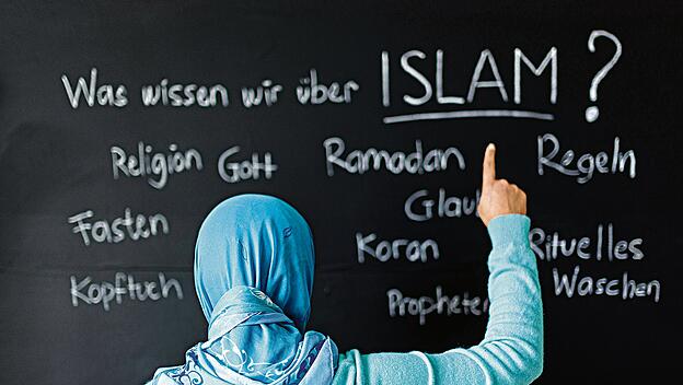 Eine muslimische Schülerin vor einer Tafel mit Begriffen aus dem Islam im Islamunterricht