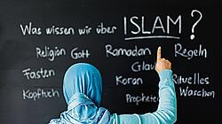 Eine muslimische Schülerin vor einer Tafel mit Begriffen aus dem Islam im Islamunterricht
