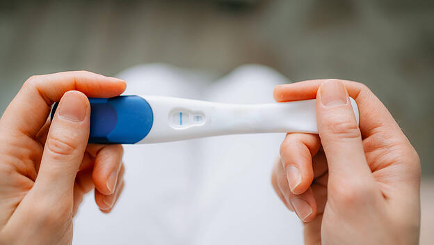 Frau mit einem Schwangerschaftstest, der ein negatives Ergebnis anzeigt.