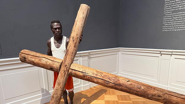 Dieser barfüßige Asmat-Mann befindet sich in einem Raum voller religiöser Gemälde aus dem 15. und 16. Jahrhundert im Lakenhal Museum Leiden: Dort wirkt die lebensechte Skulptur wie ein Aufeinandertreffen zweier sakraler Kulturen. Das lebensgroße Kreuz ist Verweis auf die Kreuzigung Jesu – als Opfer für die Ewigkeit. Auch die Asmat glauben, dass Leben nur durch die Toten möglich ist.