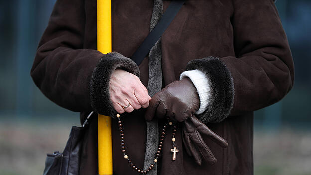 Frau betet Rosenkranz in der Öffentlichkeit